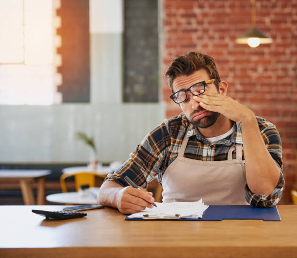 Frustrated small business owner surrounded by paperwork